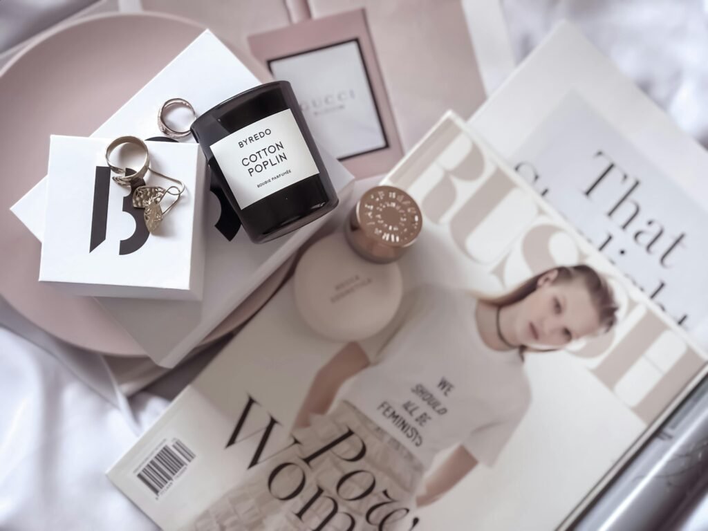 Stylish flat lay featuring fashion magazines, Byredo candle, and accessories.