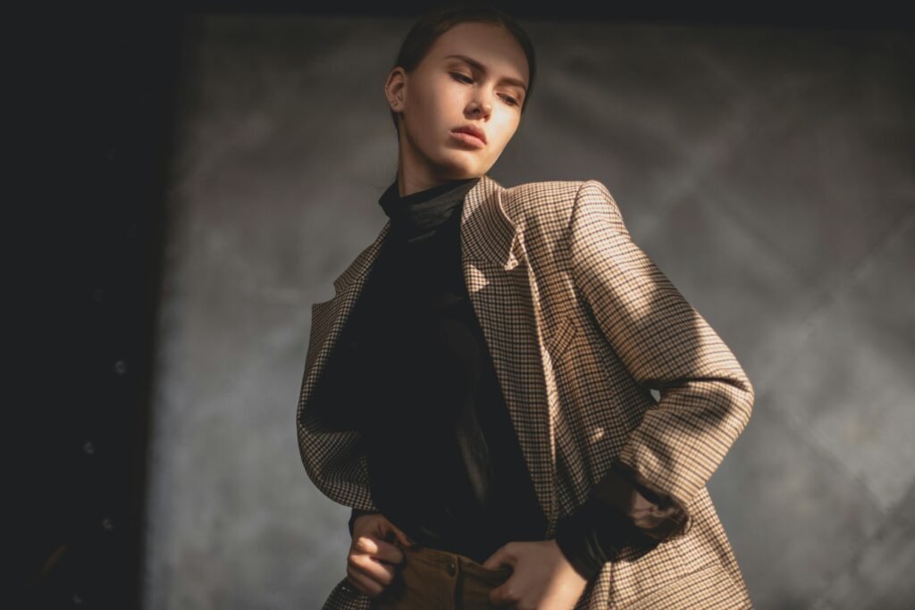 Elegant portrait of a young woman wearing a checkered coat, posing indoors with soft lighting.